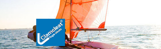 Voilier avec des voiles orange sur l'eau, illustrant l'équipement de voile légère proposé par Yachting Thommeret pour dériveurs et catamarans de sport.