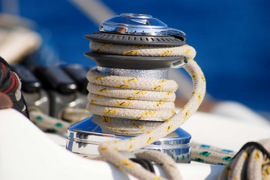 Gros plan sur un cordage enroulé autour d'un winch sur un voilier, illustrant l'équipement nautique spécialisé pour la voile légère.