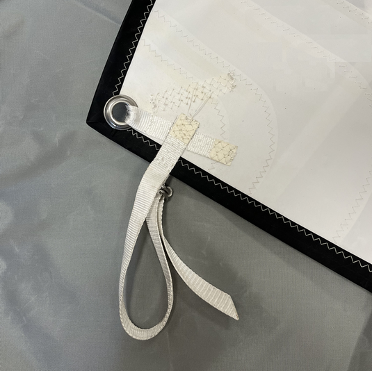 Détail du point d'amure de la voile avec une sangle pour améliorer la tension sur le mât de topaz argo.