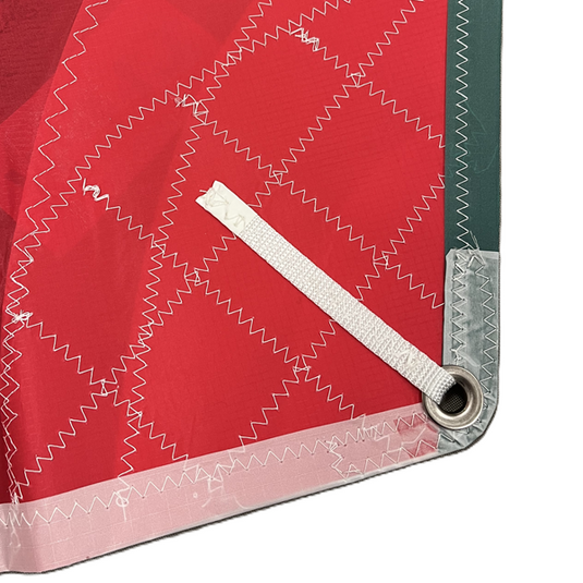 Gros plan sur le Spi Dériveur 420 Standard, montrant le coin en tissu ripstop rouge, renforcé, avec œillet métallique et sangle en nylon.